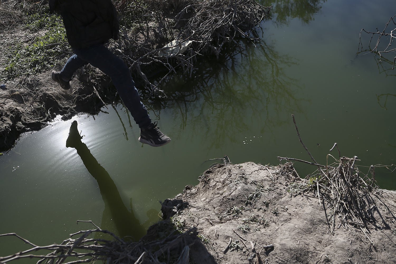  A migrant jumps over the Rio Grande river into the United States from Ciudad Juarez, Mexico, March 29, 2023, a day after dozens of migrants died in a fire at a migrant detention center in Ciudad Juarez. (AP Photo/Christian Chavez) 
