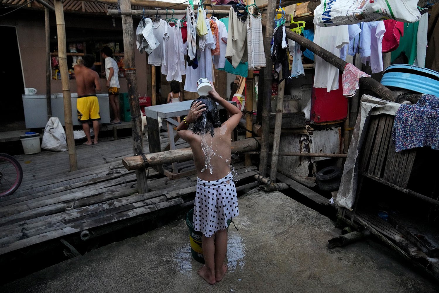  A girl takes a bath near a manual water pump at a slum area in Muntinlupa, Philippines, March 21, 2023. (AP Photo/Aaron Favila) 