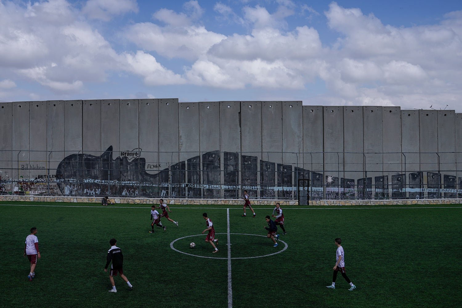  Palestinian youth play soccer in a field next to Israel's separation barrier in Aida Refugee camp, in the West Bank city of Bethlehem, Wednesday, March 8, 2023. (AP Photo/Mahmoud Illean) 
