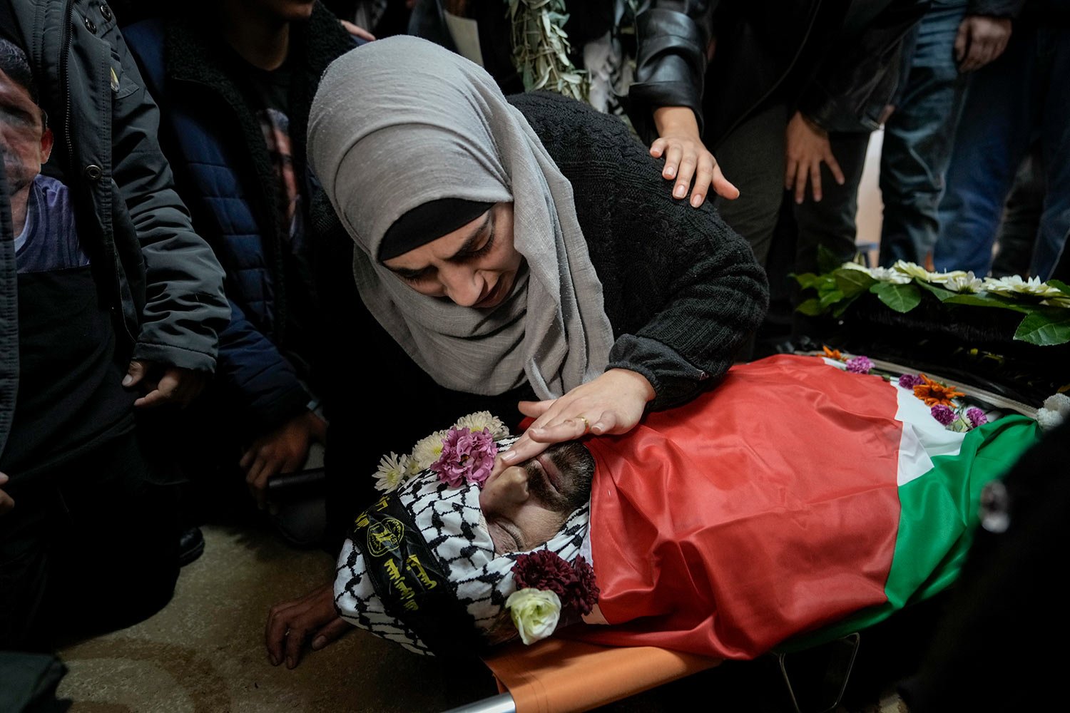  A Palestinian wife takes a last look at the body of her husband, Tariq Maali, 42, who was shot and killed by an Israeli settler after allegedly trying to stab him on Jan. 21, 2023 in the occupied West Bank, during his funeral in the village Kafr Nam