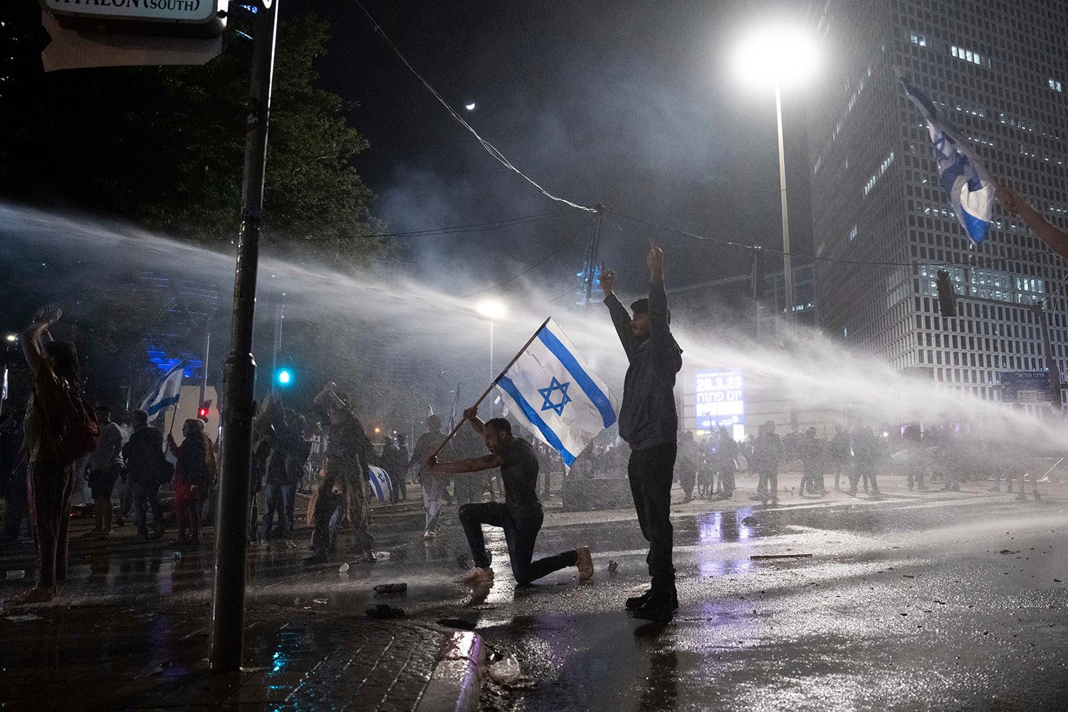  Israeli police use a water cannon to disperse demonstrators blocking a road during a protest against plans by Prime Minister Benjamin Netanyahu's government to overhaul the judicial system, in Tel Aviv, Israel, Monday, March 27, 2023. (AP Photo/Oded