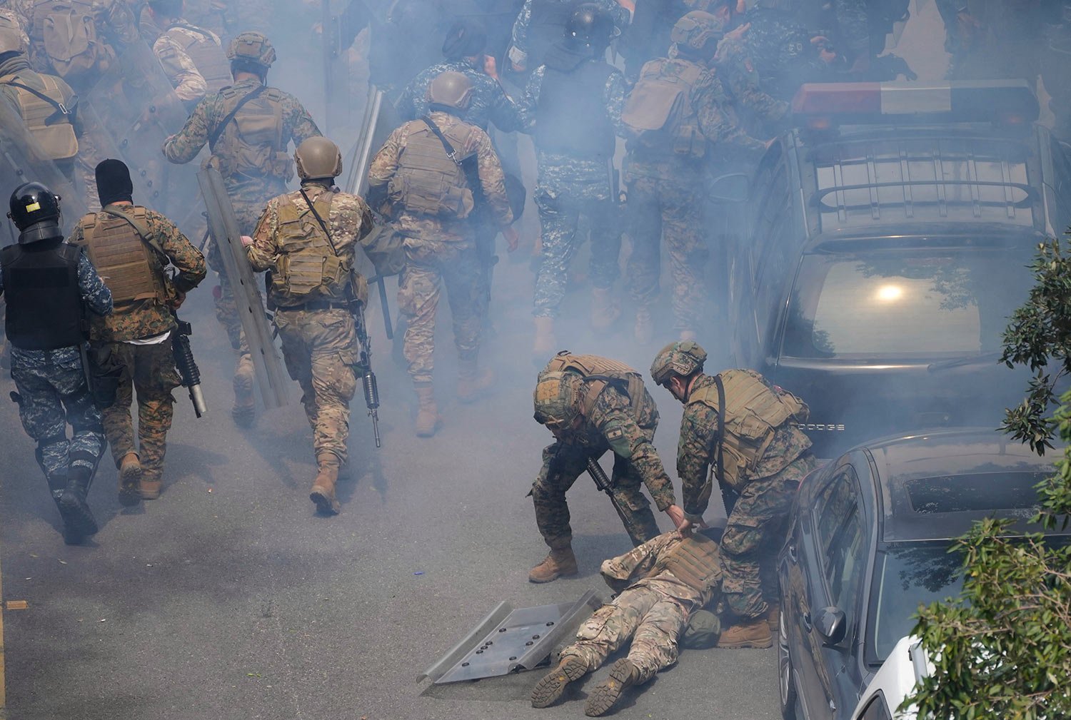  Lebanese special forces soldiers, right, remove their comrade who fainted from tear gas during a protest for retired army soldiers and other protesters who are demanding better pay, in Beirut, Lebanon, Wednesday, March 22, 2023. (AP Photo/Hussein Ma