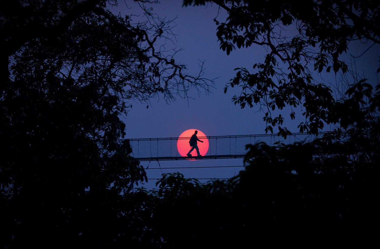  A man crosses a suspension bridge at sunset  in Bhaktapur, Nepal, Wednesday, April 12, 2023. (AP Photo/Niranjan Shrestha) 