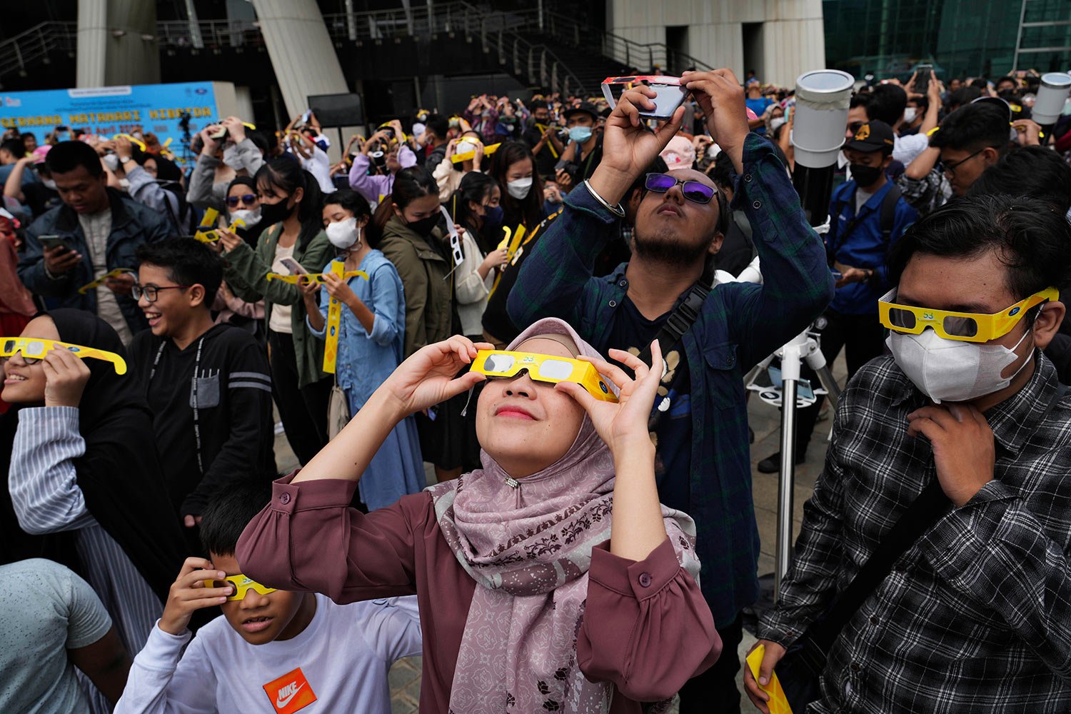  People use protective glasses to watch solar eclipse in Jakarta, Indonesia, Thursday, April 20, 2023.  (AP Photo/Tatan Syuflana) 