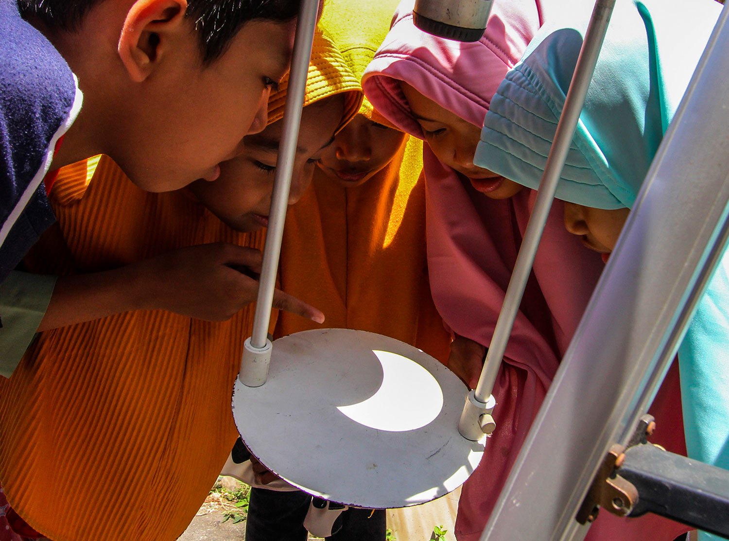  Children watch solar eclipse reflected on the base of a telescope in Yogyakarta, Indonesia, Thursday, April 20, 2023. (AP Photo/Slamet Riyadi) 