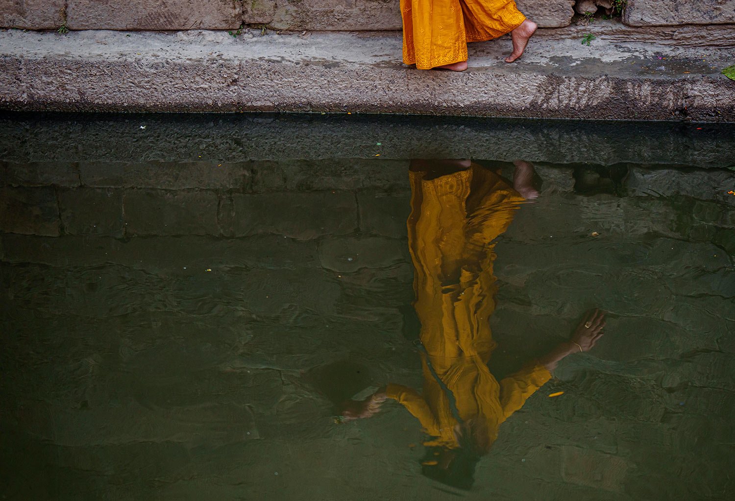  A Hindu devotee makes her way back through a narrow ledge on the banks of the Bagmati river after offering prayers in front of an idol of Astamatrika, representing eight divine mother goddesses, at the Pashupatinath temple premises in Kathmandu, Nep