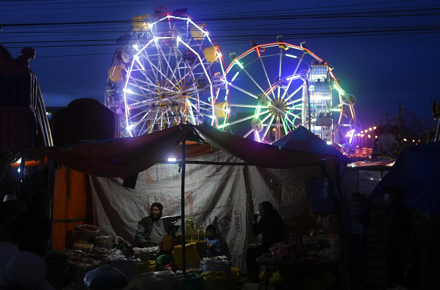  A food vendor waits for customers at the Palm Fair in El Alto, Bolivia, April 2, 2023. The fair, which began as a way to recreate the livestock markets of biblical times, is dominated by all sorts of informal trade. (AP Photo/Juan Karita) 