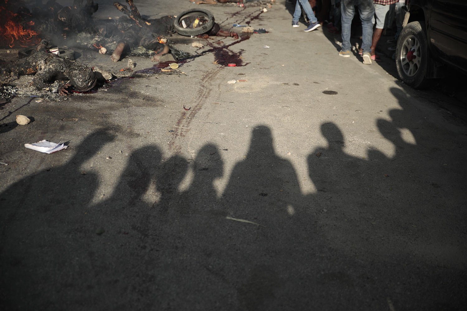  Bystanders gather around the bodies of alleged gang members who were set on fire by a mob after they were stopped by police while traveling in a vehicle in the Canape Vert area of Port-au-Prince, Haiti, April 24, 2023. (AP Photo/Odelyn Joseph) 