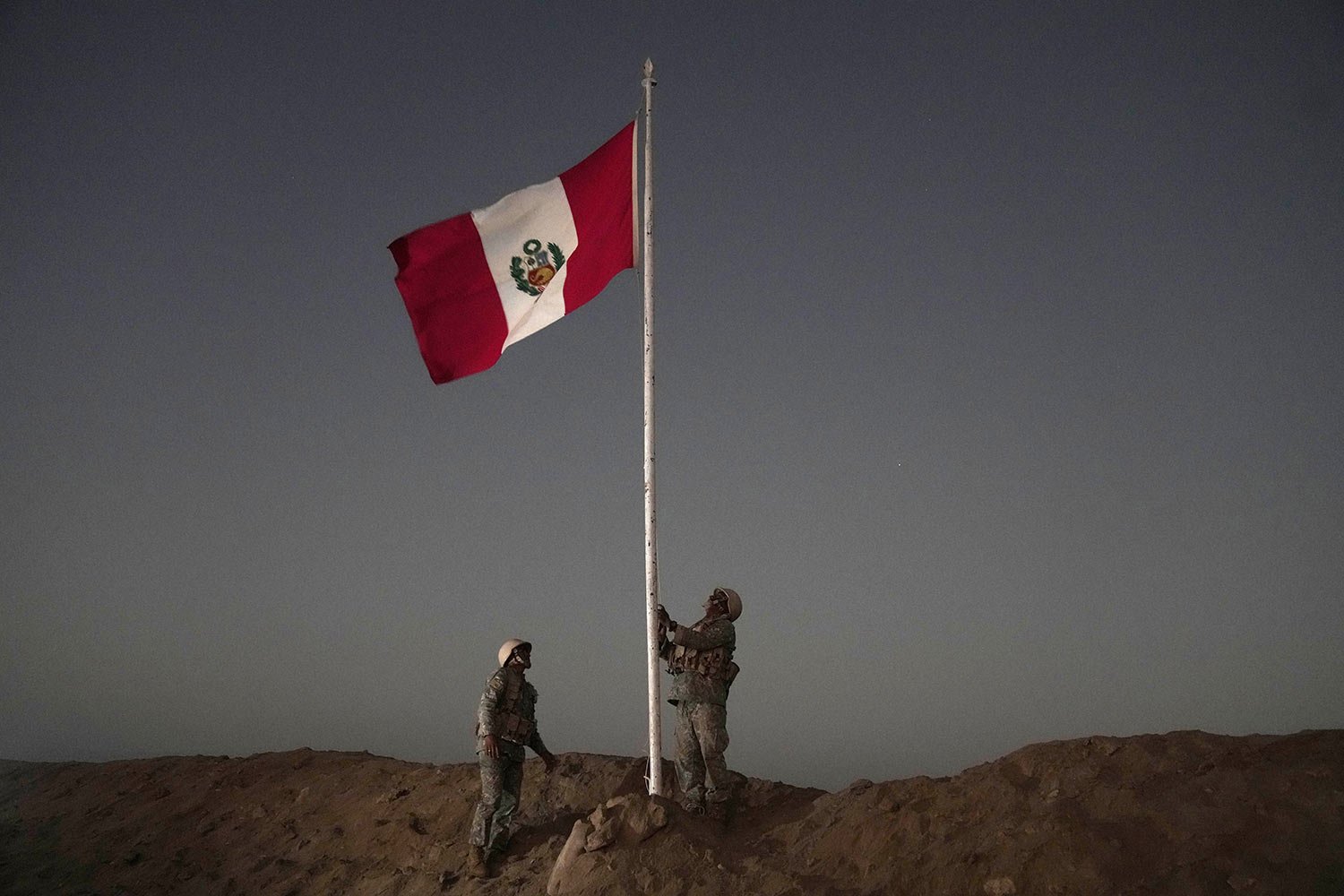  Peruvian soldiers raise their country's flag on the border with Chile in Tacna, Peru, April 28, 2023. A migration crisis at the border between Chile and Peru intensified as hundreds of migrants remained stranded, unable to cross into Peru. (AP Photo