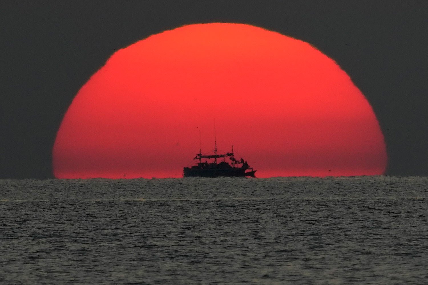  A fishing boat passes by a setting sun in the Sulu Sea, as seen onboard Philippine Coast Guard BRP Malabrigo while it heads to Philippine-occupied areas at nearby South China Sea on Tuesday, April 18, 2023. (AP Photo/Aaron Favila) 