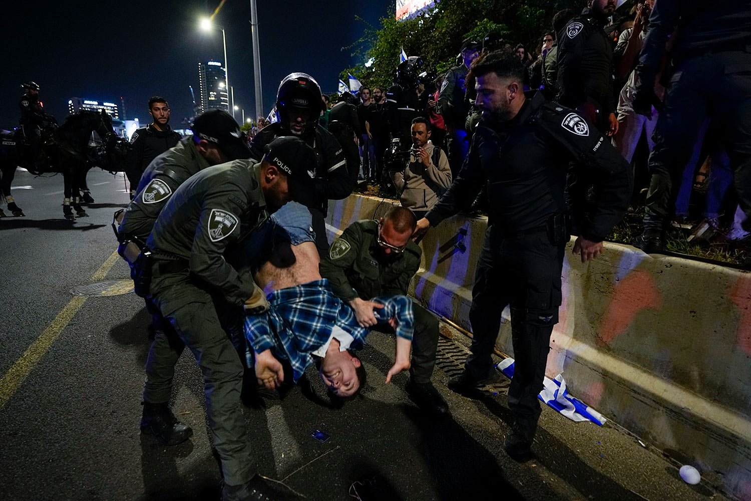 Israeli police officers disperse demonstrators blocking a highway during a protest against plans by Prime Minister Benjamin Netanyahu's government to overhaul the judicial system in Tel Aviv, Saturday, April 15, 2023. (AP Photo/Ariel Schalit) 