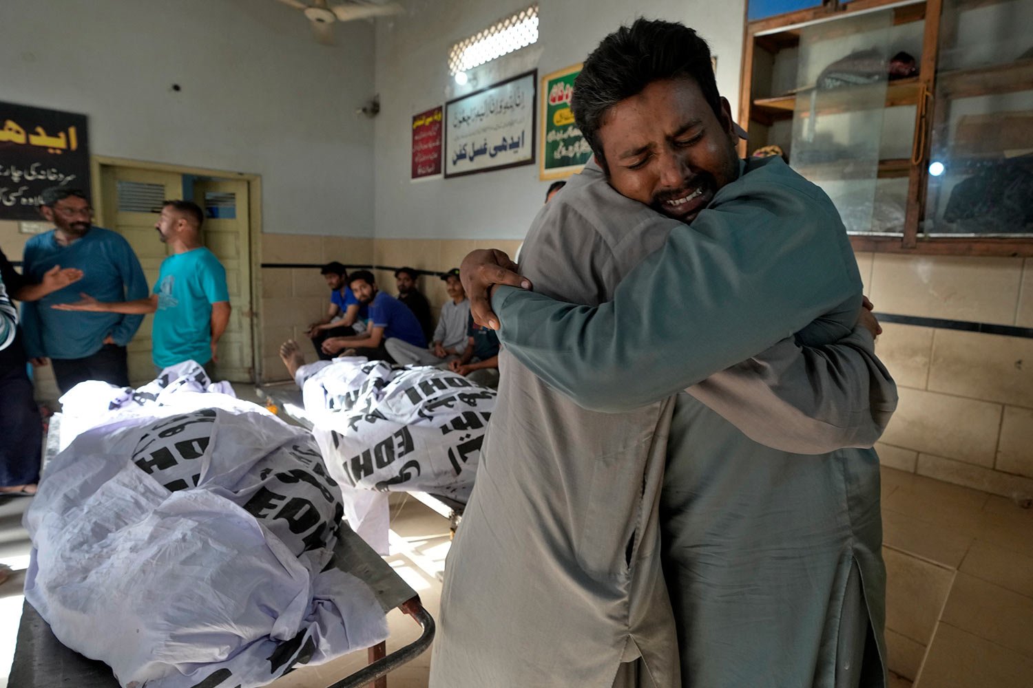  People mourn next to the bodies of firefighters, who died in a fire, at a morgue in Karachi, Pakistan, Thursday, April 13, 2023. (AP Photo/Fareed Khan) 