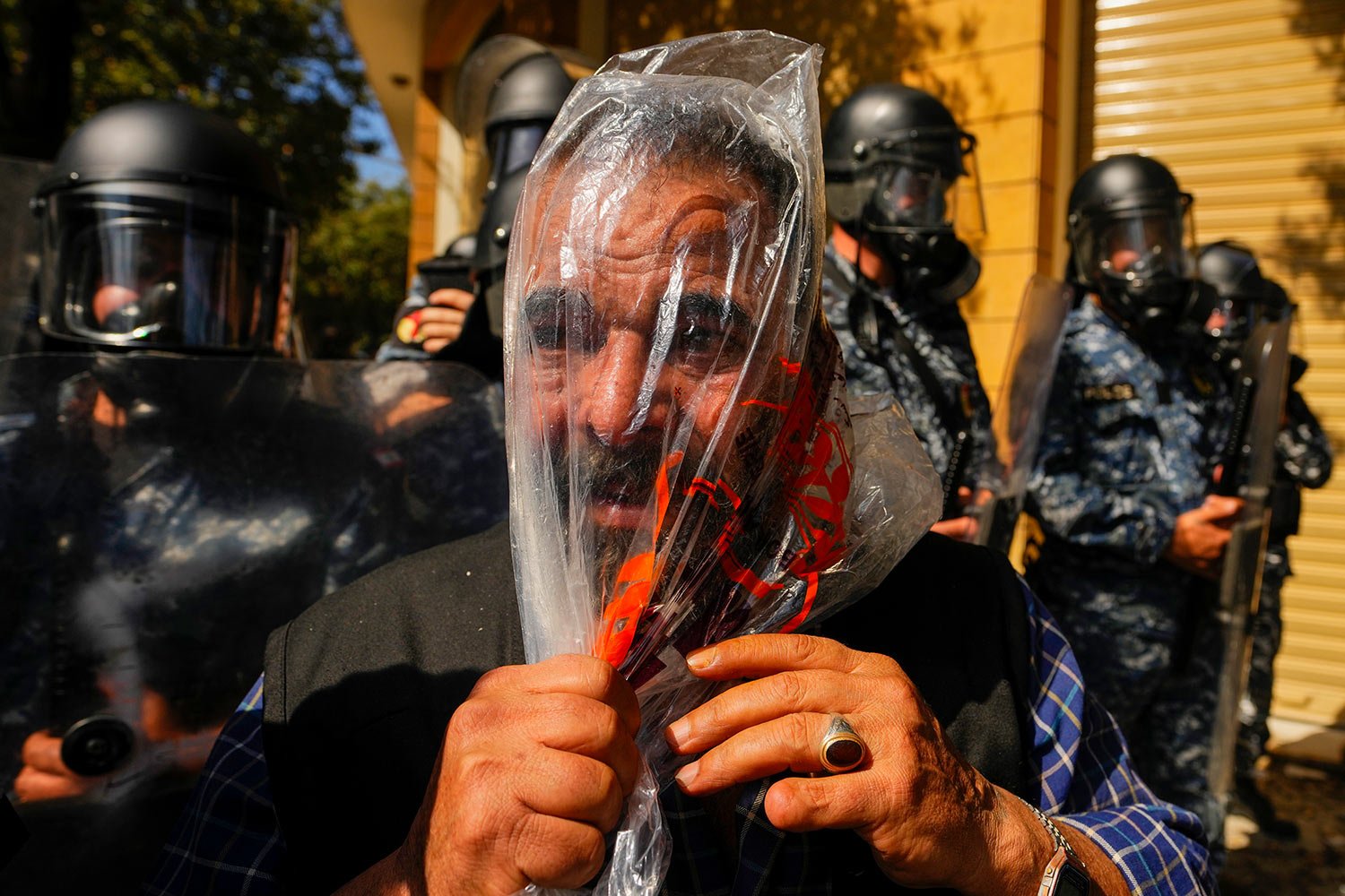  A retired member of Lebanese security forces uses a plastic bag to protect himself from tear gas during clashes with the Lebanese army and riot police during a protest in Beirut, Lebanon, Tuesday, April 18, 2023. AP Photo/Hassan Ammar) 