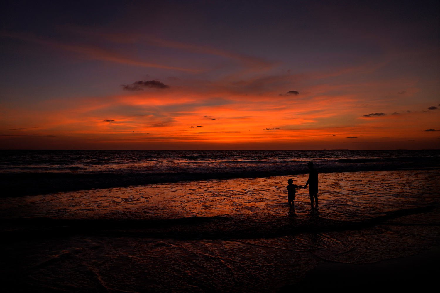  A boy holds the hand of his father as they watch the sunset at a beach in Goa, India, Wednesday, May 3, 2023. I(AP Photo/Manish Swarup) 