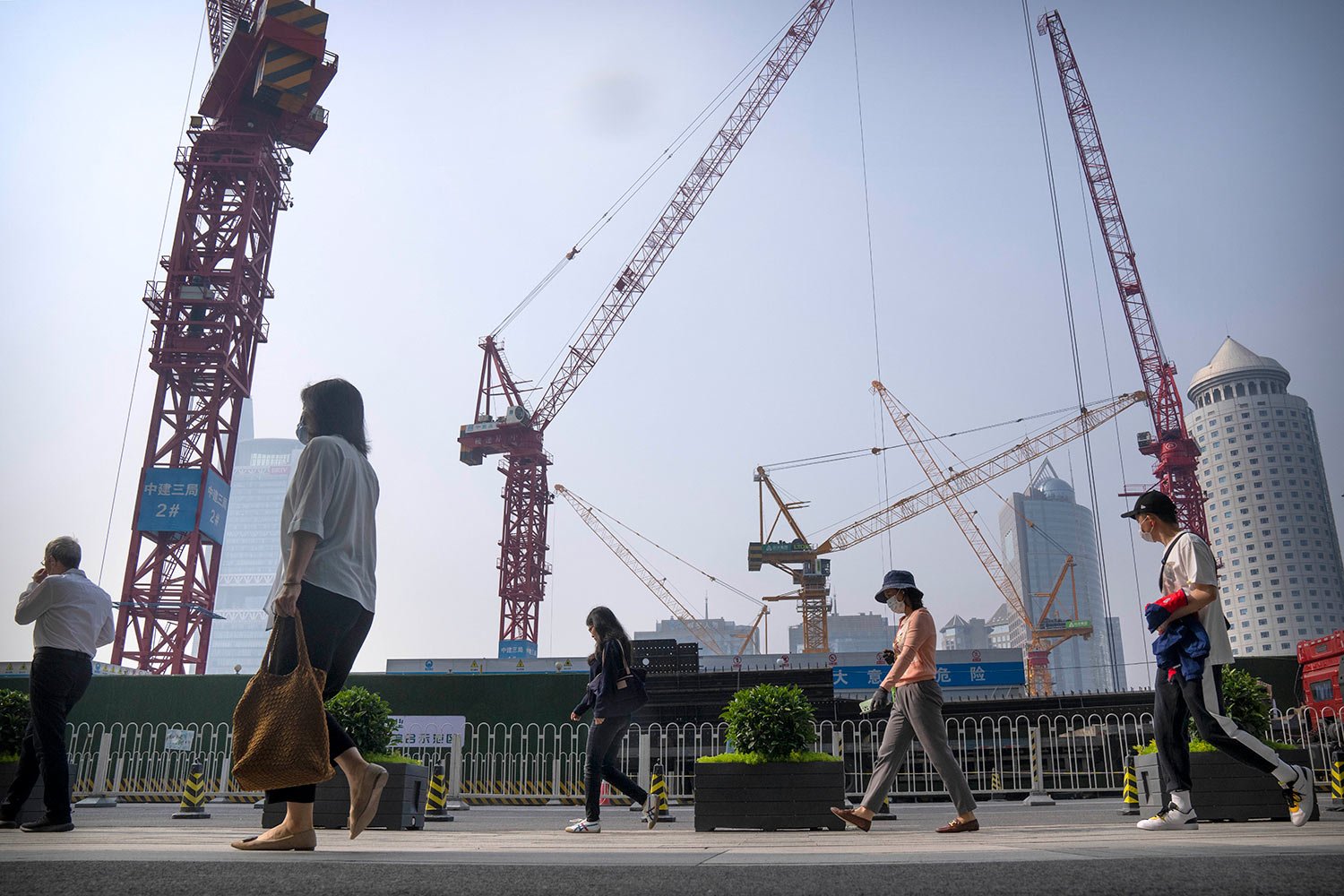 Commuters wearing face masks walk past a construction site in the central business district during the morning rush hour in Beijing, Friday, May 26, 2023. (AP Photo/Mark Schiefelbein) 