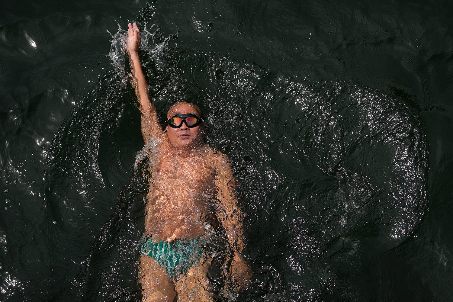  A man swims as residents cool off along a canal during a heat wave in Beijing, Sunday, May 21, 2023. (AP Photo/Andy Wong) 