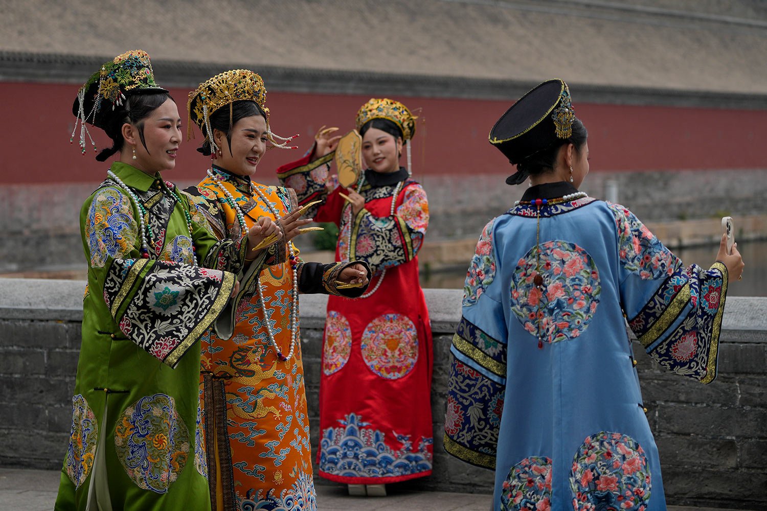  A woman films her friends wearing the empress costumes perform a dance outside the Forbidden City in Beijing, Wednesday, May 17, 2023. (AP Photo/Andy Wong) 