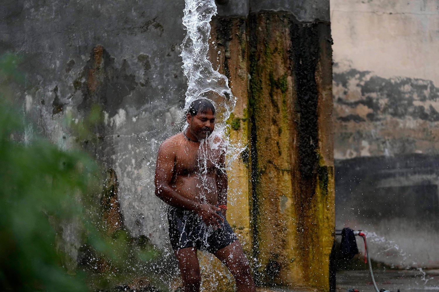  A man bathes from a roadside water tap to cool himself on a hot summer day on the outskirts of Jammu, India, Tuesday, May 16, 2023. (AP Photo/Channi Anand) 