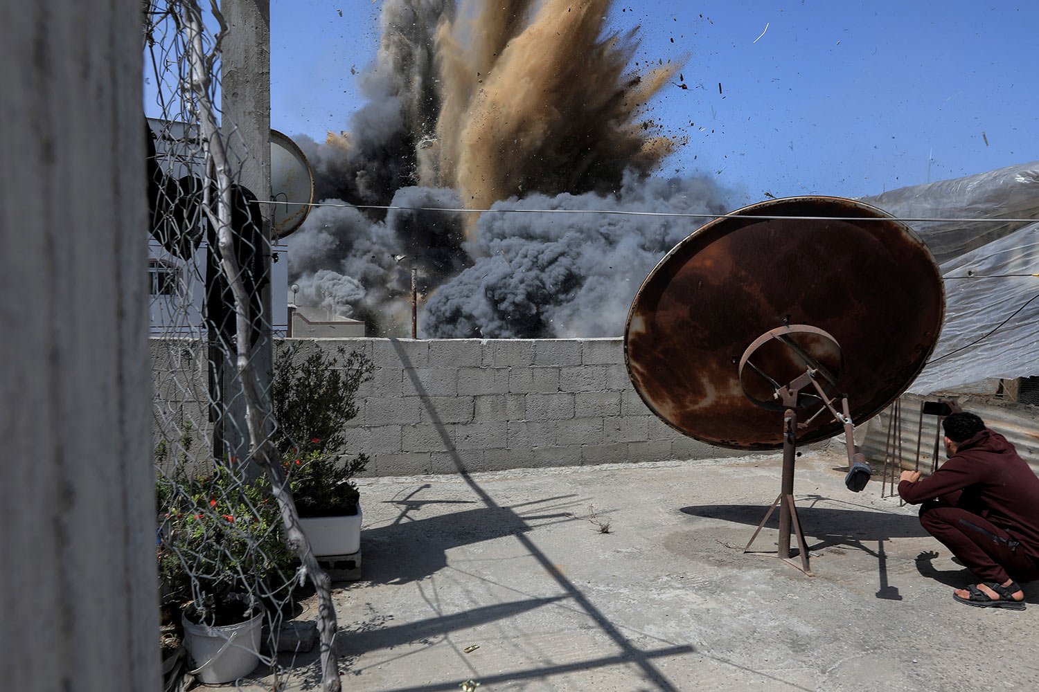  A Palestinian youth takes photos of an explosion from an Israeli airstrike targeting a nearby building, which Israel says belonged to a Palestinian Islamic Jihad militant in Beit Lahiya, northern Gaza Strip, Saturday, May 13, 2023. (AP Photo/Mohamme