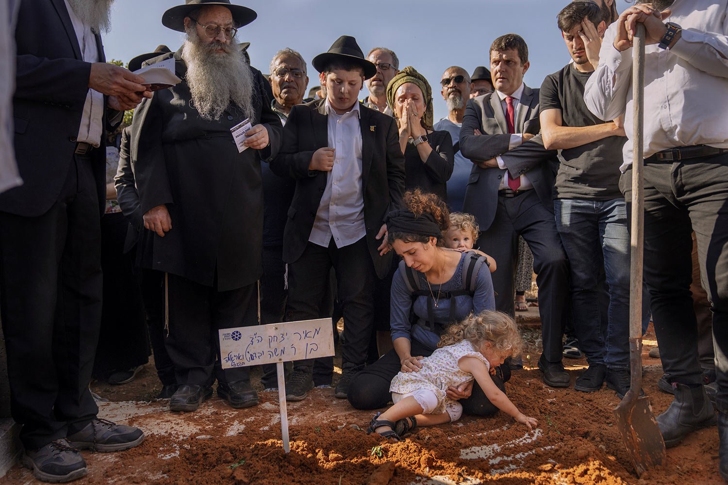  Israeli woman Tal Tamari, her two young children, and others mourn over the grave of her husband Meir Tamari, 32, during his funeral in the West Bank Jewish settlement of Shaked, Wednesday, May 31, 2023.  (AP Photo/Ohad Zwigenberg) 