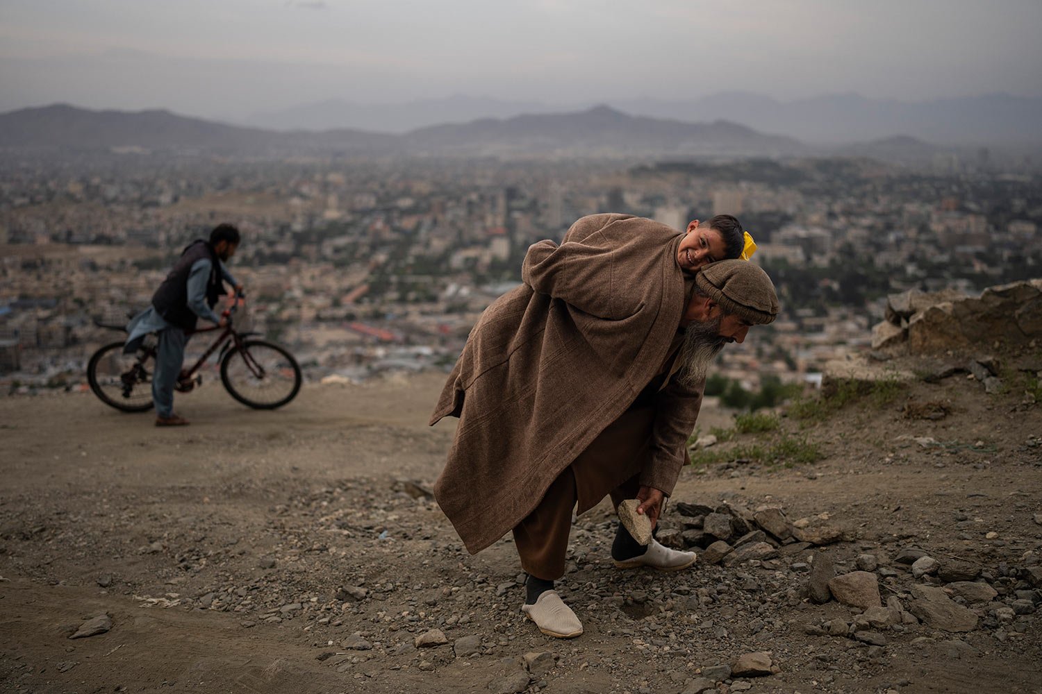  Abdul Qader Ghazizada removes stones from a dirt road in Kabul, Afghanistan, Sunday, May 28, 2023. (AP Photo/Rodrigo Abd) 