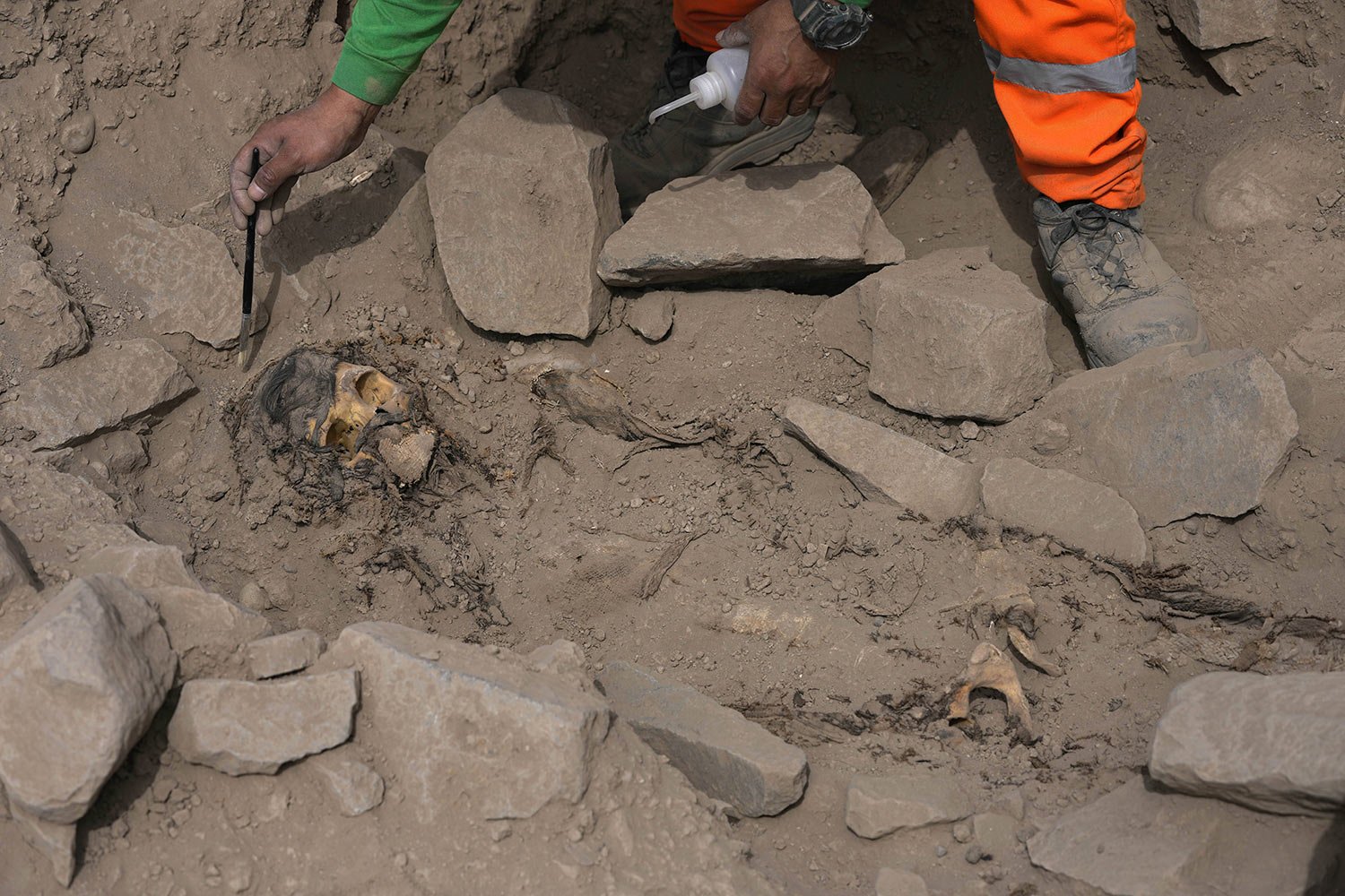 An archaeologist excavates a pre-Hispanic mummy that was discovered next to a training field for a Peruvian professional soccer team in the El Rimac neighborhood of Lima, Peru, June 15, 2023. (AP Photo/Martin Mejia)