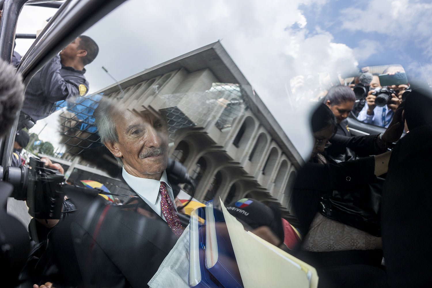 Newspaper founder and editor Jose Ruben Zamora rides in patrol car, surrounded by the press, back to prison after a court hearing in Guatemala City, Wednesday, June 14, 2023. A tribunal has convicted Zamora and sentenced him to six years in prison i