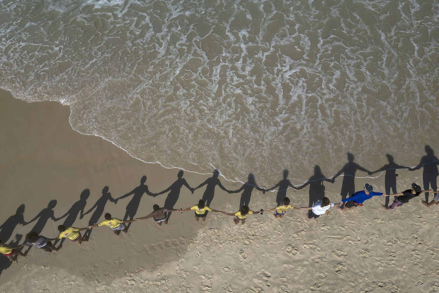 People create a line holding hands along Sao Conrado beach for a symbolic group hug with the sea, an event coined "That Hug" to draw attention to ocean pollution on World Oceans Day in Rio de Janeiro, Brazil, June 8, 2023. (AP Photo/Bruna Prado)