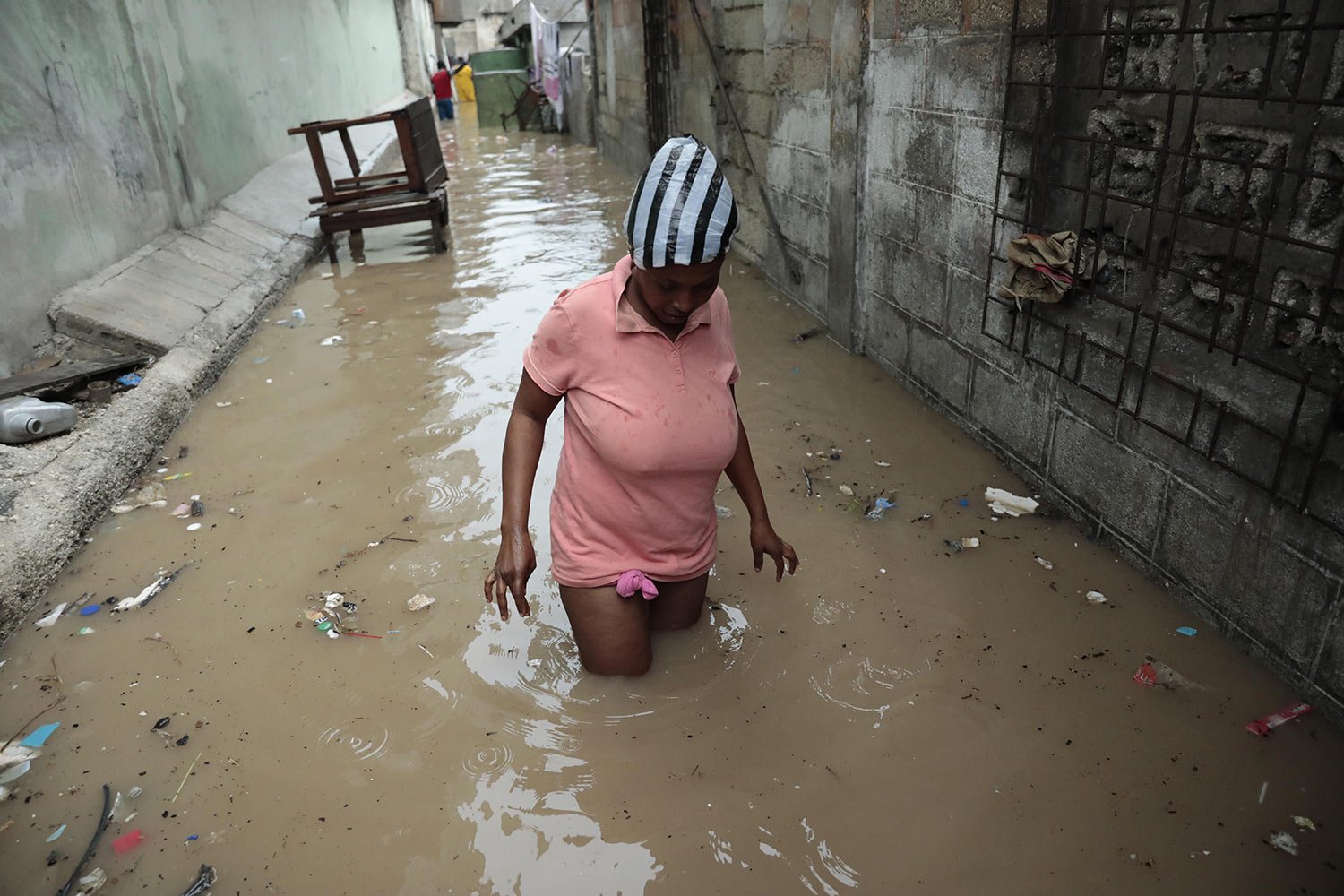 A woman wades through a flooded alleyway after a heavy rain in Port-au-Prince, Haiti, June 3, 2023. (AP Photo/Odelyn Joseph)