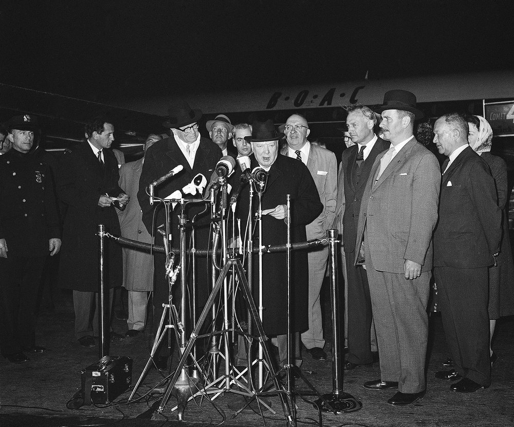  Winston Churchill, 84, reads a speech into microphones before boarding plane at New York’s Idlewild Airport for a flight to London on May 10, 1959. At left is Bernard Baruch. Man wearing glasses behind Churchill at right is James C. O’Brien, Deputy 