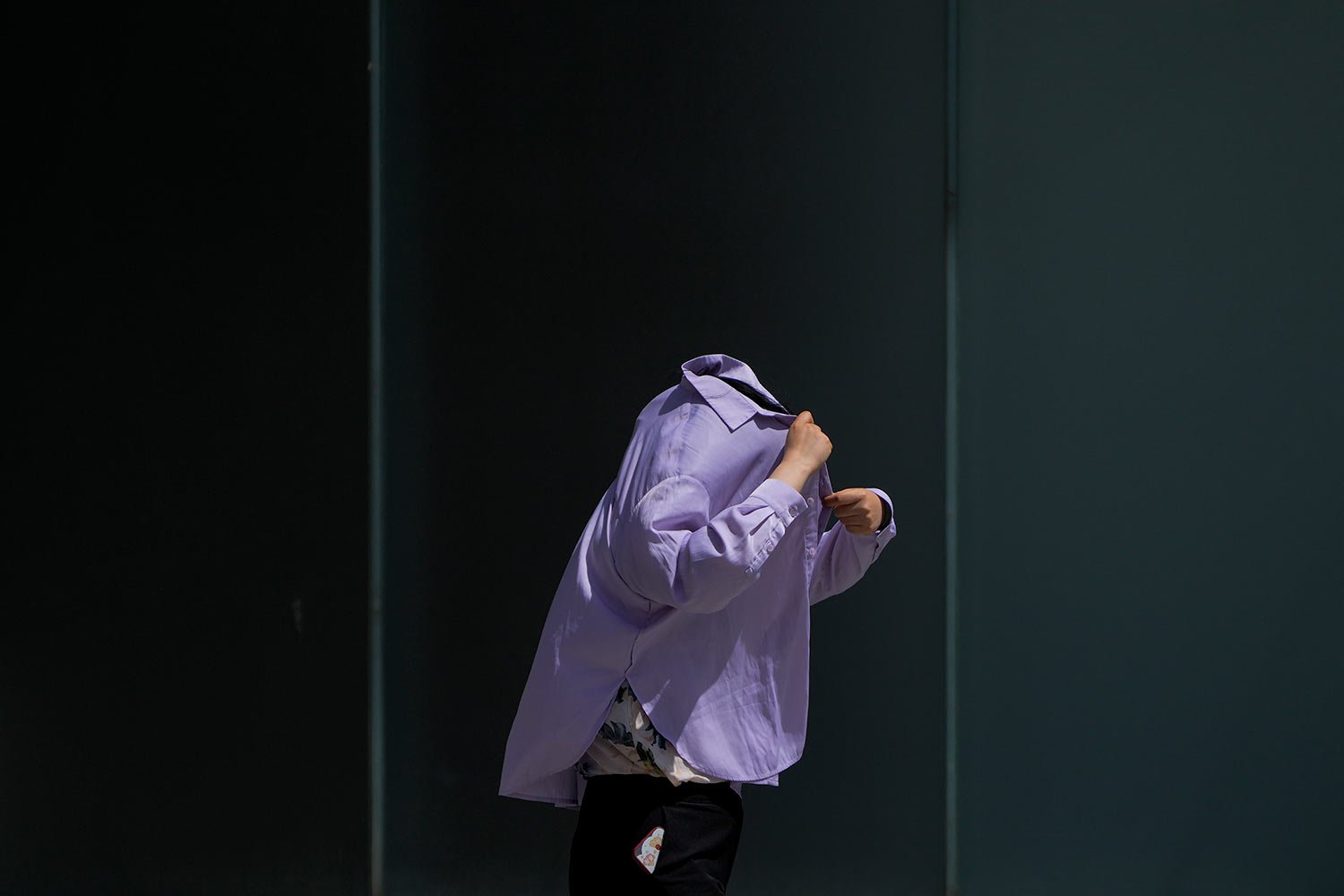 A woman uses a long-sleeve shirt to shield from the sun as she walks at an outdoor shopping mall on a sweltering day in Beijing, Thursday, July 6, 2023. (AP Photo/Andy Wong)