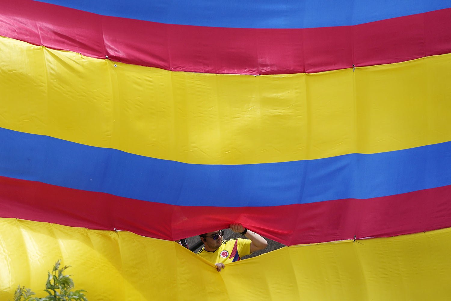  A man looks through an opening of a giant Colombian national flag during the Independence Day military parade, in Bogota, Colombia, Thursday, July 20, 2023. (AP Photo/Fernando Vergara) 