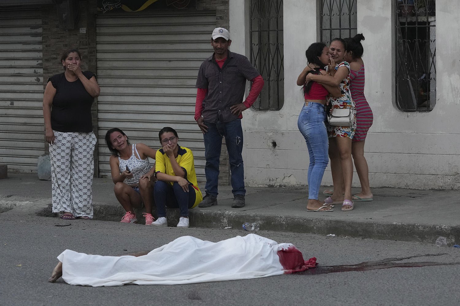  Persons grieve near the body of a man, killed in unknown circumstances, on a street in Duran, Ecuador, Friday, July 21, 2023. (AP Photo/Dolores Ochoa) 