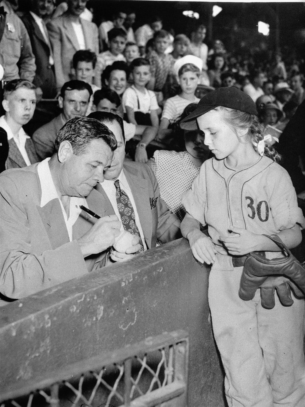  Babe Ruth, home run king of the major leagues and former right fielder for the New York Yankees, autographs a baseball for 10-year-old Monica Meehan, who plays right field for a Philadelphia midget team.  The Babe was the guest of honor today, July 