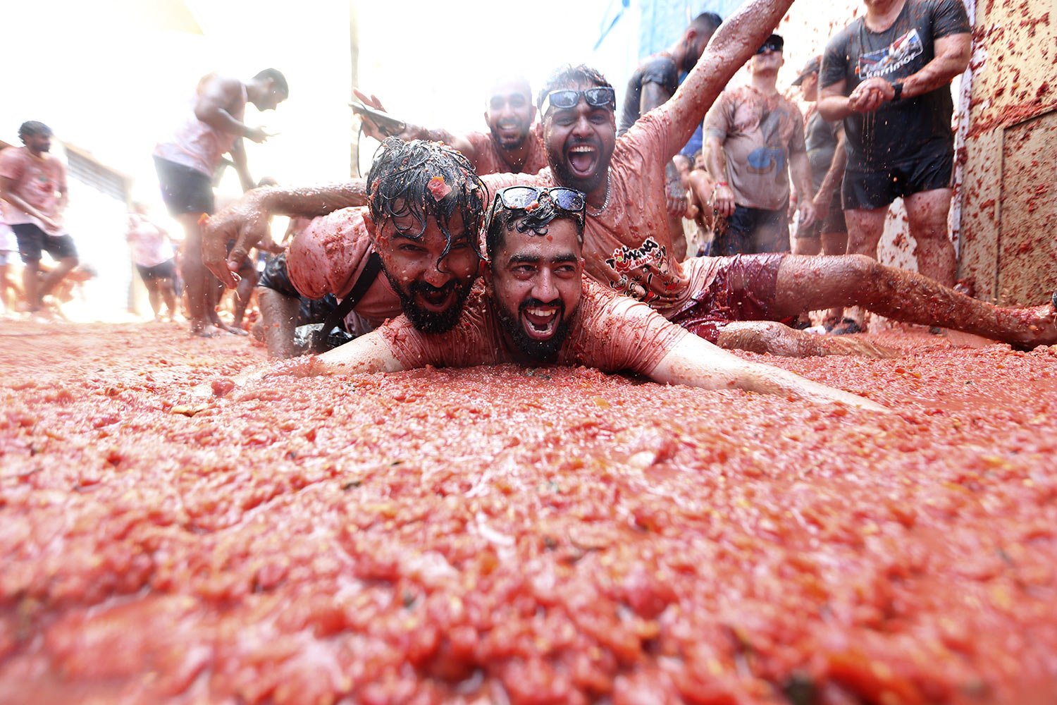  People slide on a carpet of red tomato pulp, in Bunol, Spain, Wednesday, Aug. 30, 2023. (AP Photo/Alberto Saiz) 