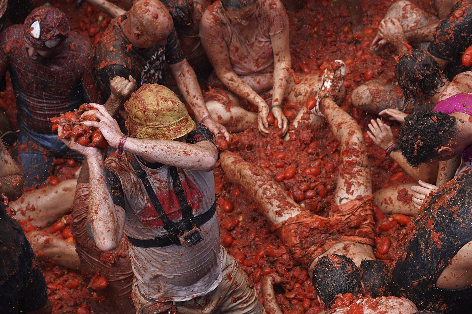  A man winds up with a handful of overripe tomatoes to hurl at participants in the annual “Tomatina” festival, in Bunol, Spain, Wednesday, Aug. 30, 2023. (AP Photo/Alberto Saiz) 