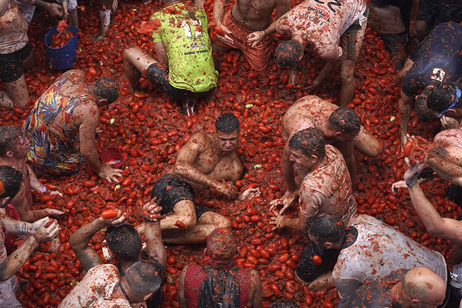  Participants bask in puddles of squashed tomatoes during the annual "Tomatina" street battle, in Bunol, Spain, Wednesday, Aug. 30, 2023. (AP Photo/Alberto Saiz) 