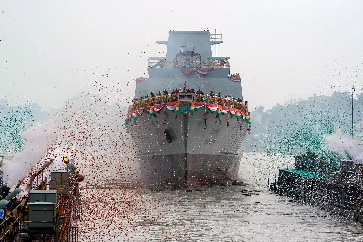 Confetti and smoke in the colors of the Indian national flag mark the entry of INS Vindhyagiri, a new warship for the Indian navy, into the Hooghly river in Kolkata, India, Thursday, Aug. 17, 2023. (AP Photo/Bikas Das)