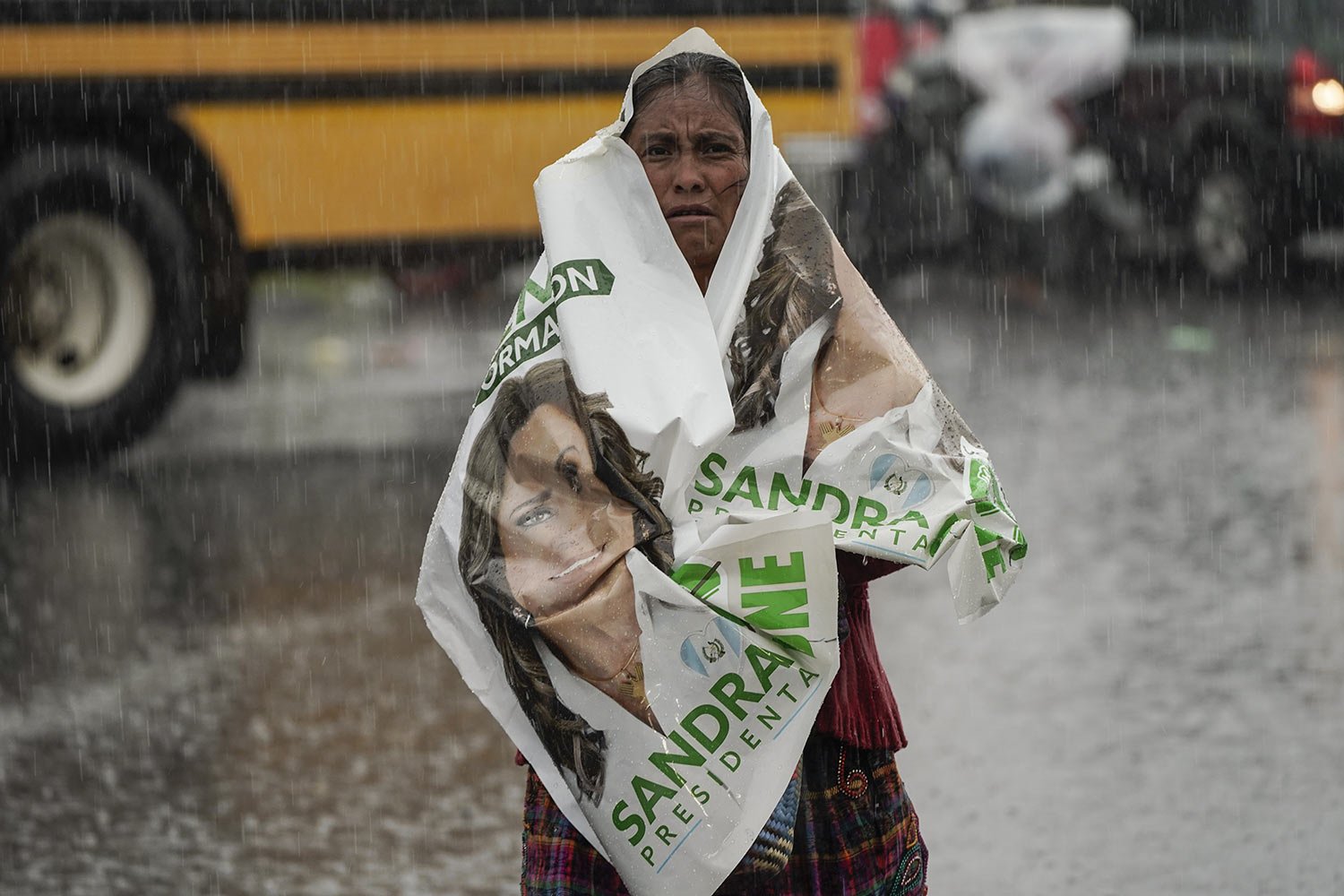  A woman covers herself in the rain with an election banner of presidential hopeful Sandra Torres after attending her campaign rally in Chimaltenango, Guatemala, Aug. 13, 2023, ahead of the Aug. 20 runoff election. (AP Photo/Moises Castillo) 