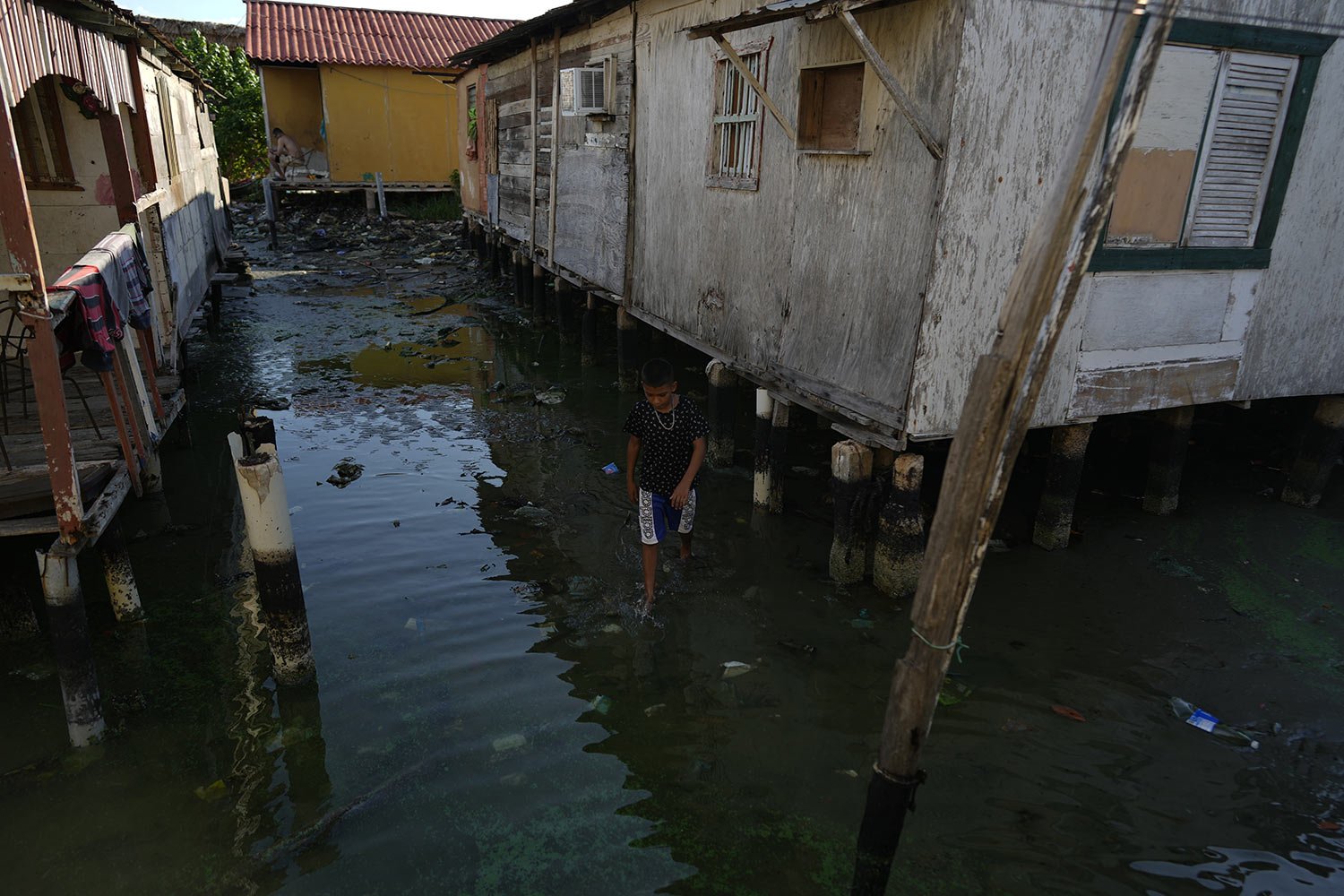  A boy walks between stilt houses, on the water's edge of Lake Maracaibo in the Santa Rosa de Agua neighborhood of Maracaibo, Venezuela, Aug. 8, 2023. (AP Photo/Ariana Cubillos) 