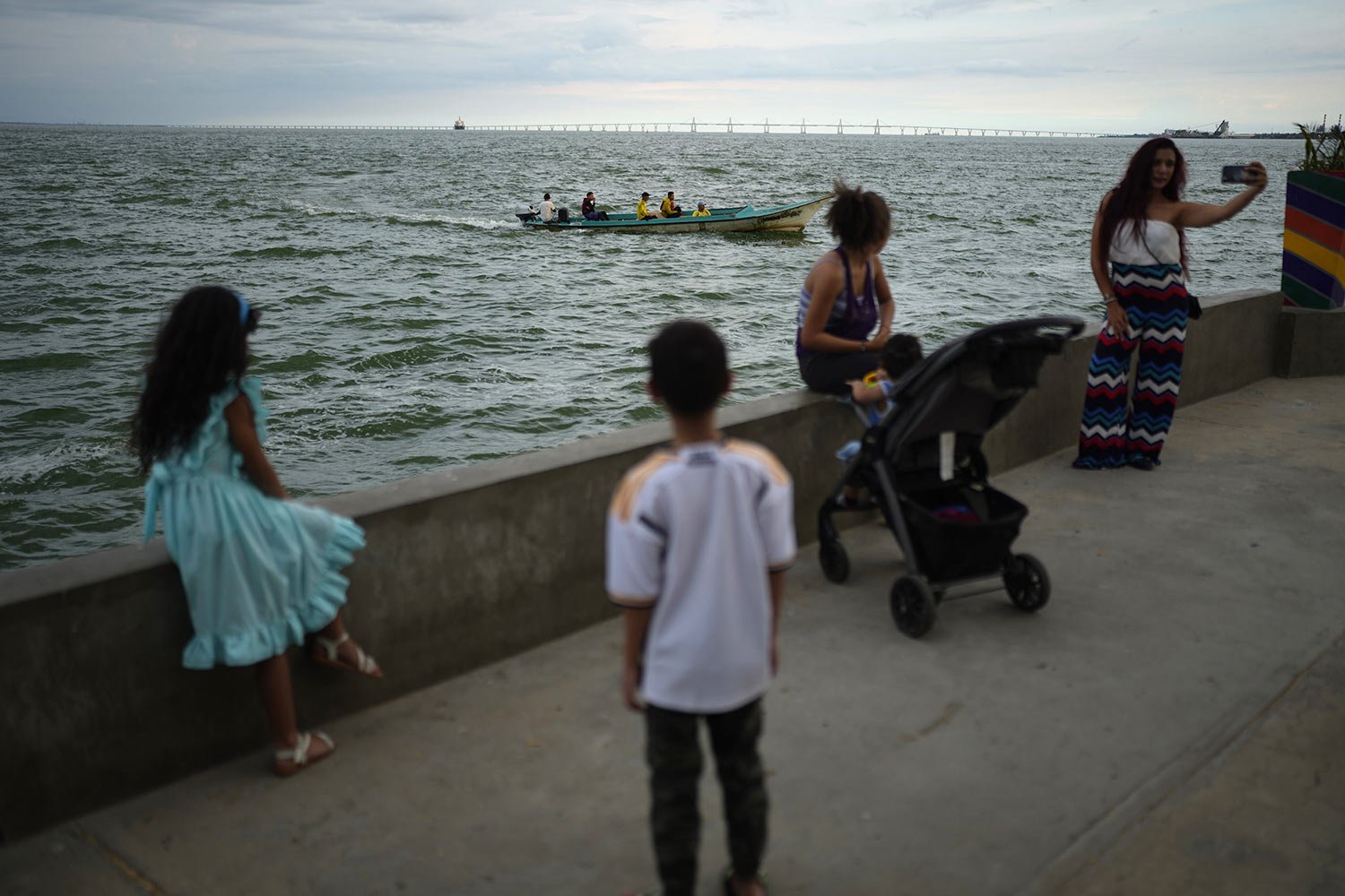  Residents gather on a seawall as passengers ride a boat on Lake Maracaibo, in Maracaibo, Venezuela, Aug. 10, 2023. (AP Photo/Ariana Cubillos) 