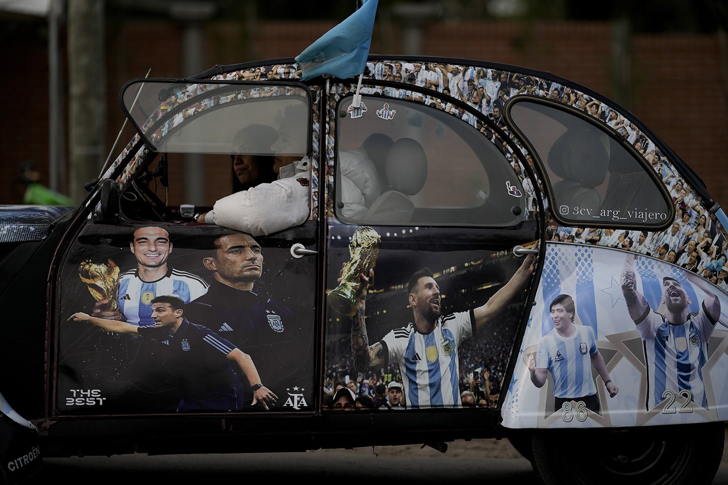  A couple sits in a Volkswagen beetle decorated with the image of Argentina soccer star Lionel Messi and coach Lionel Scaloni, outside the Argentina Soccer Association in Buenos Aires, Argentina, Sept. 5, 2023. (AP Photo/Natacha Pisarenko) 