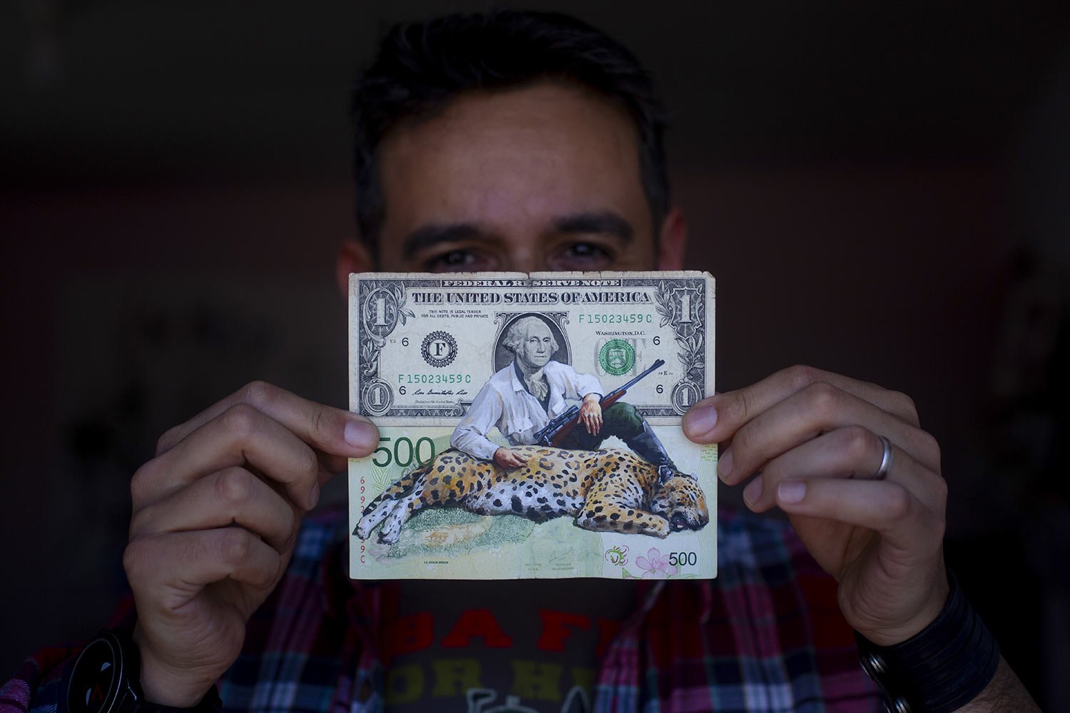  Artist Sergio Díaz holds up a piece of his money art featuring a U.S. dollar and an Argentine 500-peso note with former U.S. President George Washington holding a rifle alongside a dead jaguar, at his studio in Salta, Argentina, Sept. 9, 2023. As mi