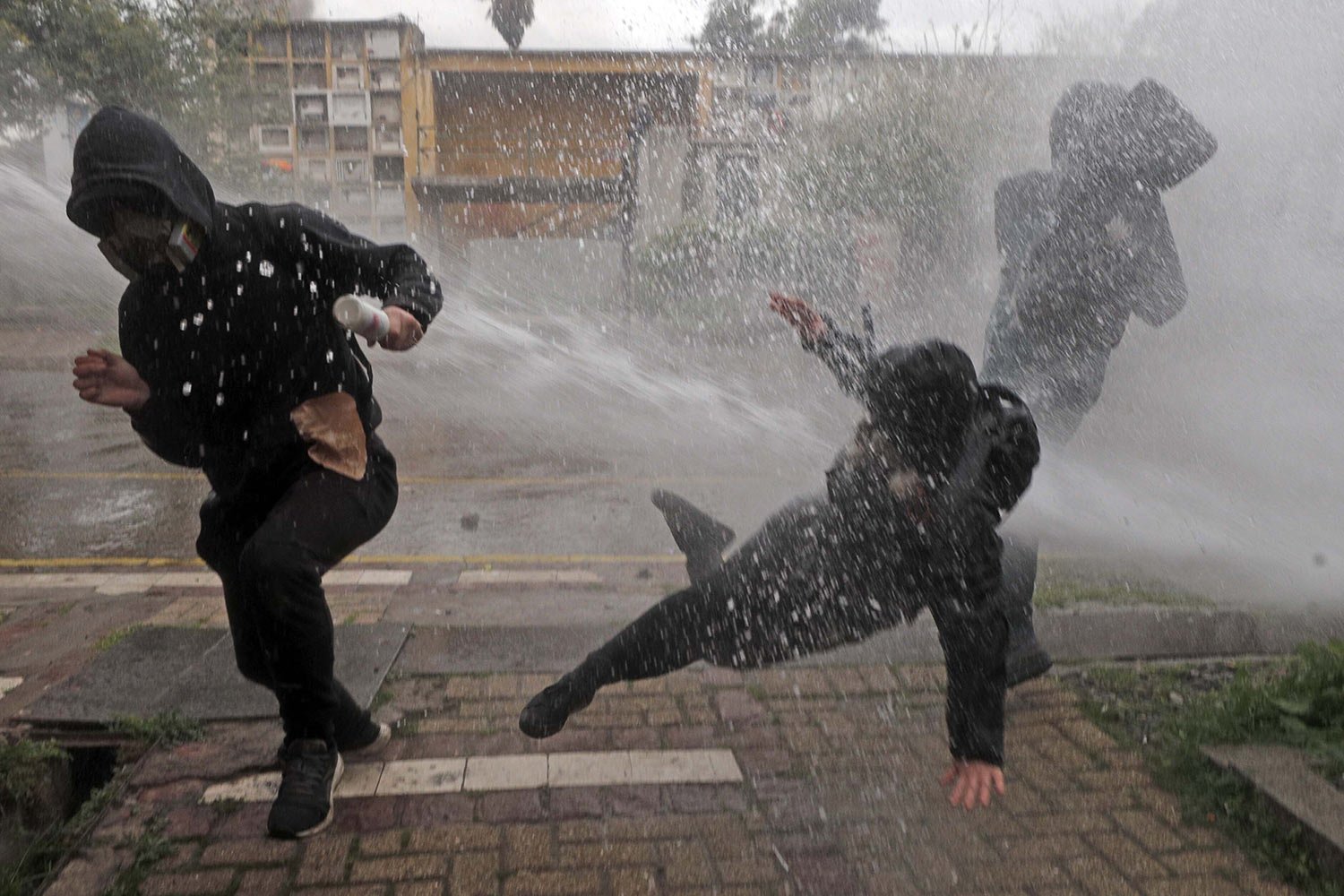  Protesters are hit by a police water cannon during clashes at a march marking the 50th anniversary of a military coup led by Gen. Augusto Pinochet in Santiago, Chile, Sept. 10, 2023. (AP Photo/Luis Hidalgo) 