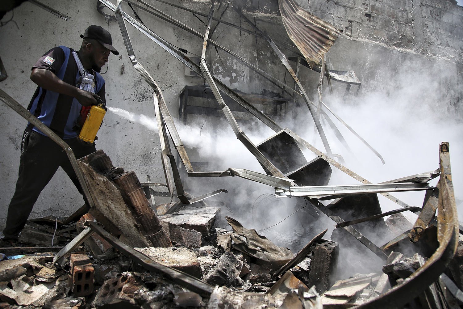  A worker extinguishes a smoldering fire in what is left of a spare parts warehouse after a deadly car bomb exploded behind a nearby police station in Timba, Cauca, Colombia, Sept. 20, 2023. (AP Photo/Andres Quintero) 