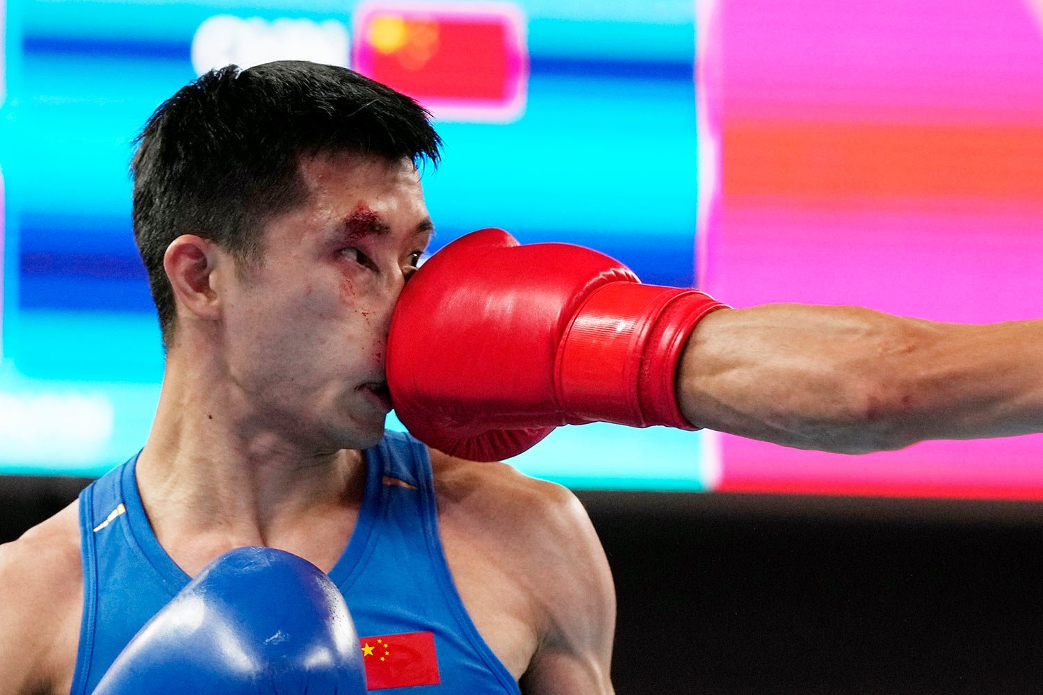 Lyu Ping of China, left, takes a punch from Abdumalik Khalokov of Uzbekistan, right, during boxing Men's 51-57Kg semifinal match at the 19th Asian Games in Hangzhou, China, Hangzhou, Wednesday, Oct. 4, 2023. (AP Photo/Aijaz Rahi) 