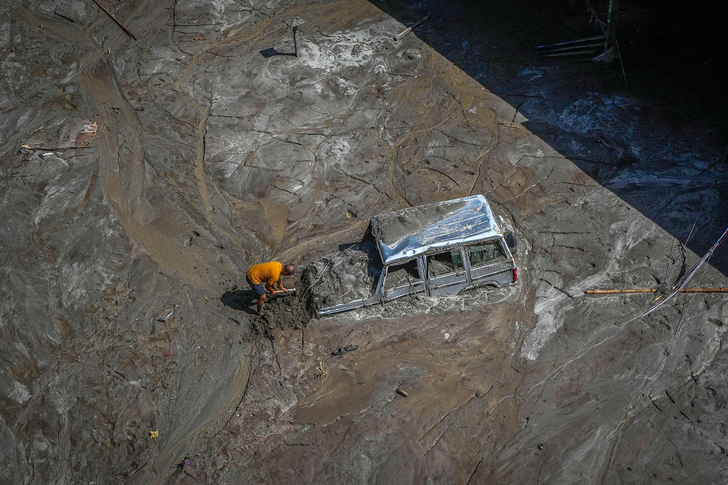  A man digs as he tries to recover a vehicle submerged in mud in the flood affected area along the Teesta river in Rongpo, east Sikkim, India, Sunday, Oct. 8. 2023.  (AP Photo/Anupam Nath) 