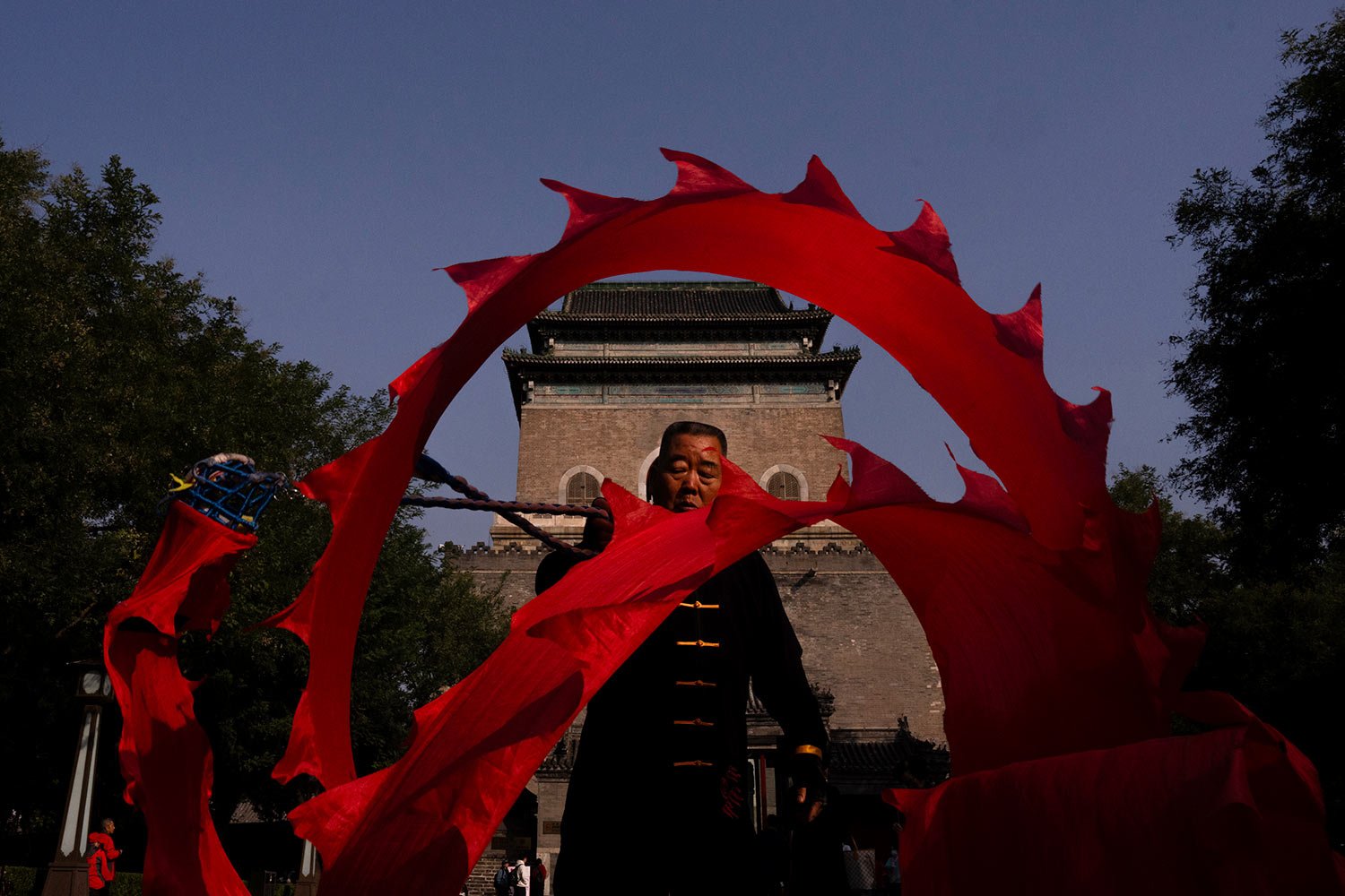  A person swings a dragon ribbon near the Bell Tower in Beijing, Tuesday, Oct. 17, 2023. (AP Photo/Louise Delmotte) 