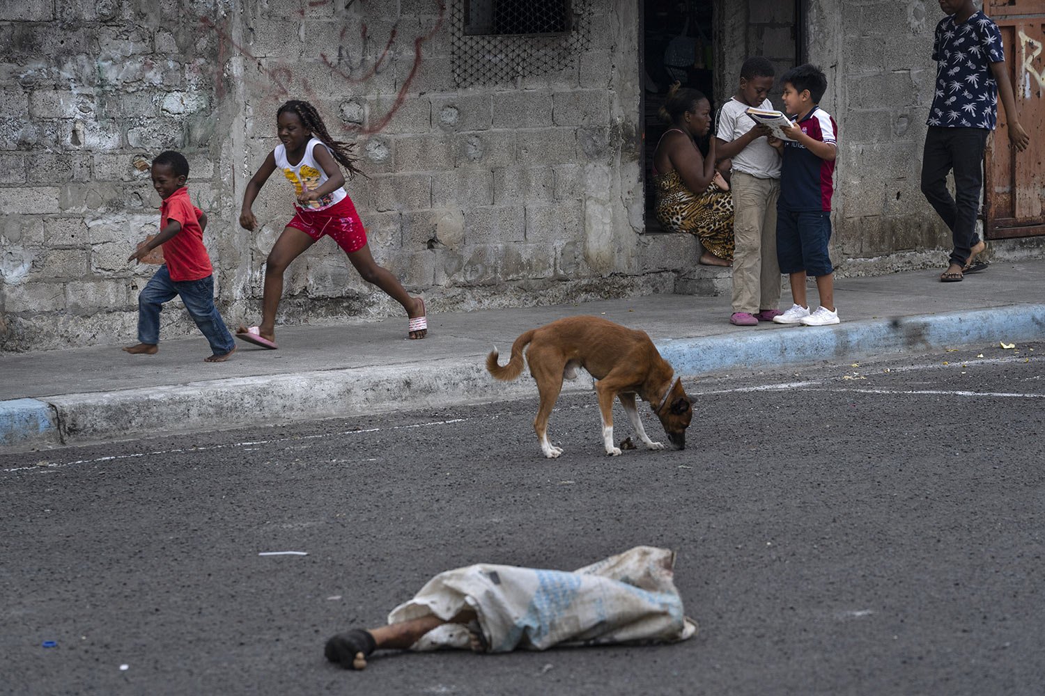  The legs of a dismembered man protrude from a bag on the street where children play and dogs roam in the Colinas de La Florida neighborhood in Guayaquil, Ecuador, Oct. 1, 2023. The legs laid there for hours before being picked up by authorities and 