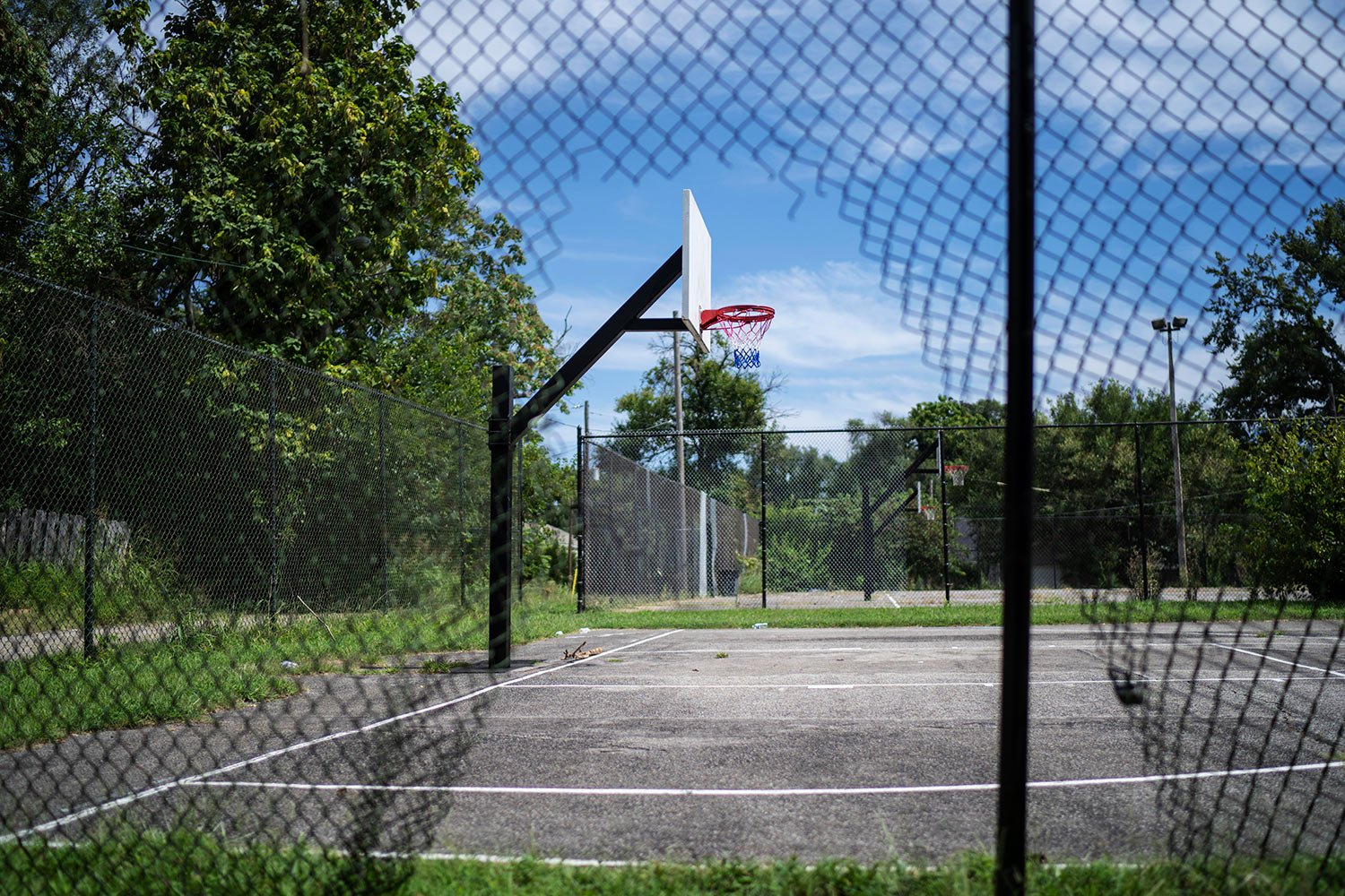  A whole in a fence frames a basketball hoop at Ballard park where Victoria Gwynn was shot and injured in 2021 in Louisville, Ky, Tuesday, Aug. 29, 2023. The 17-year-old friend she was there to meet was killed. (AP Photo/David Goldman)  